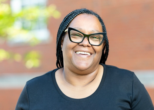 Smiling Black woman with cat-eye glasses.